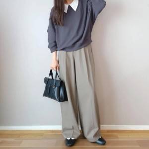  グレーのトップスにベージュのパンツを合わせた女性 