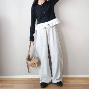  黒カーディガンにグレーのパンツを合わせた女性 