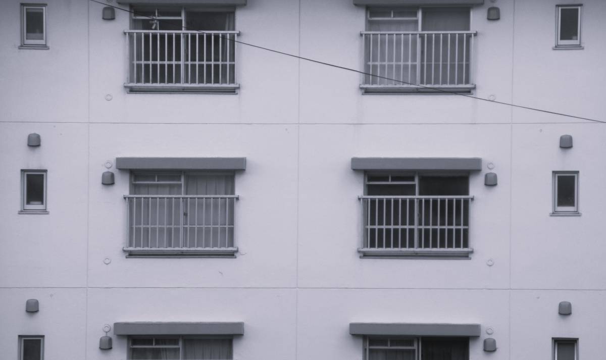 同じ形の窓とベランダが規則正しく並ぶ、集合住宅の外観。