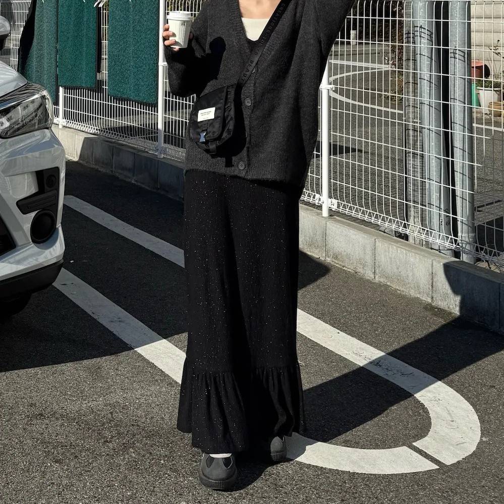 グレーのカーディガンに黒スカートを合わせた女性