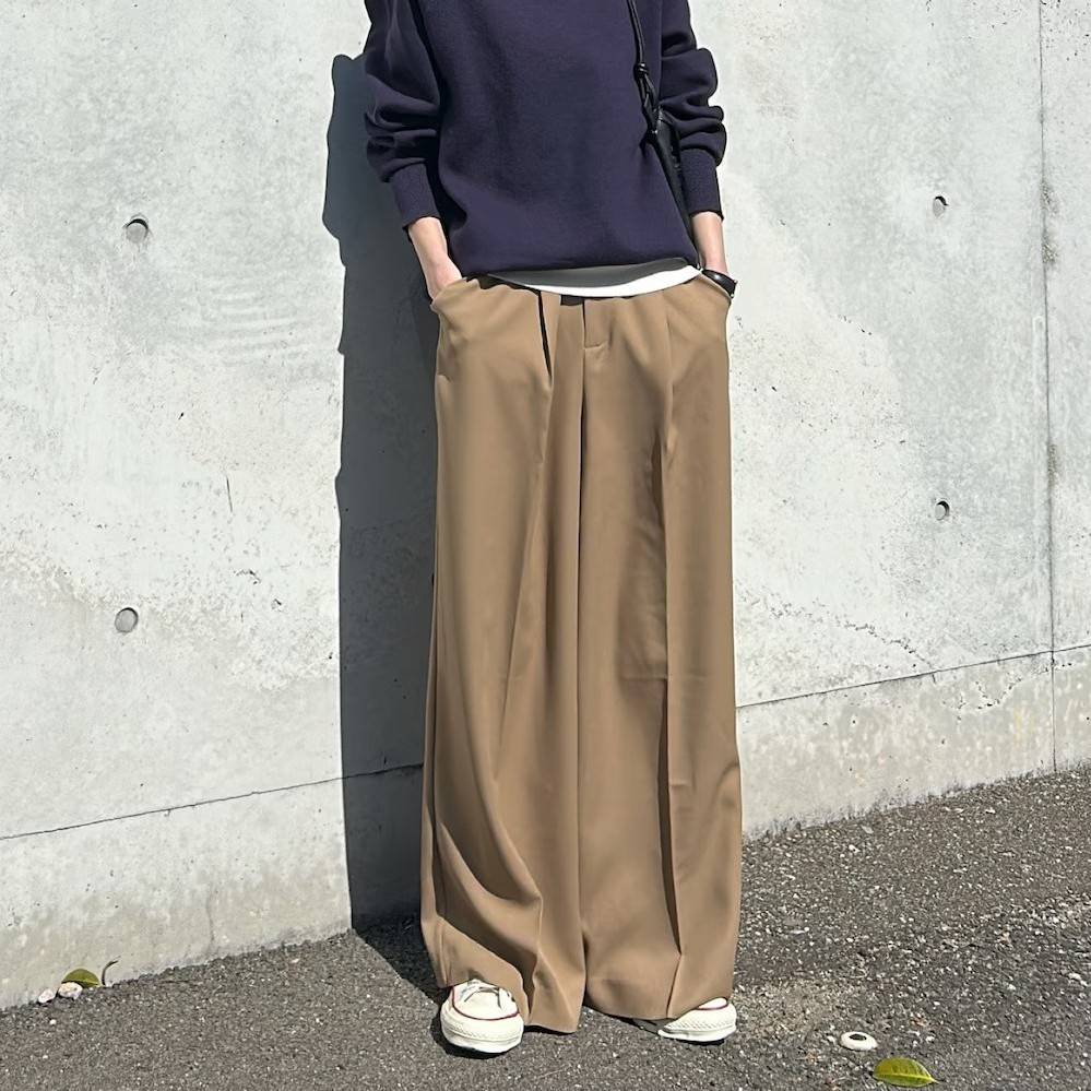 ネイビーのスウェットにベージュのパンツを合わせた女性