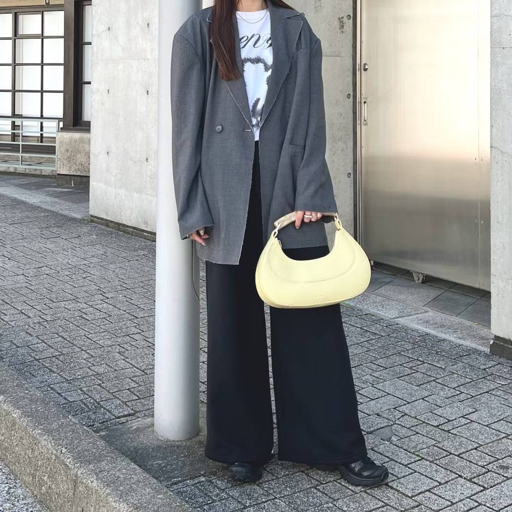 グレーのジャケットに黒パンツを合わせた女性
