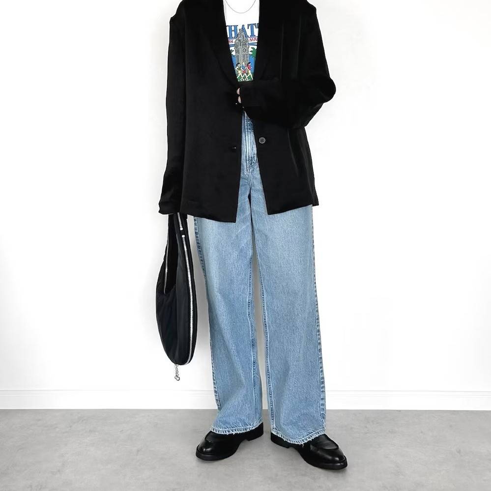 黒のジャケットにデニムパンツを合わせた女性