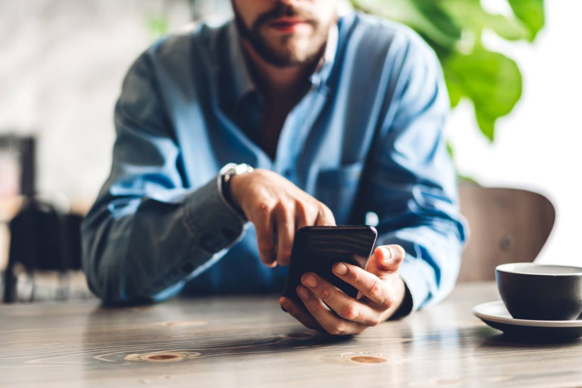 カフェでスマートフォンを操作する男性の手元