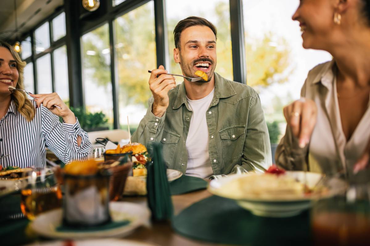友だちとレストランで食事する男性