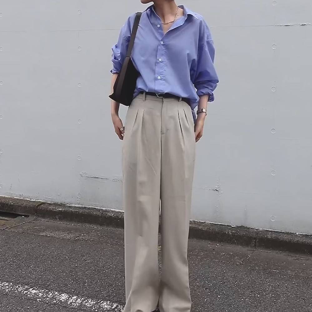 ブルーのシャツにベージュのパンツを合わせた女性