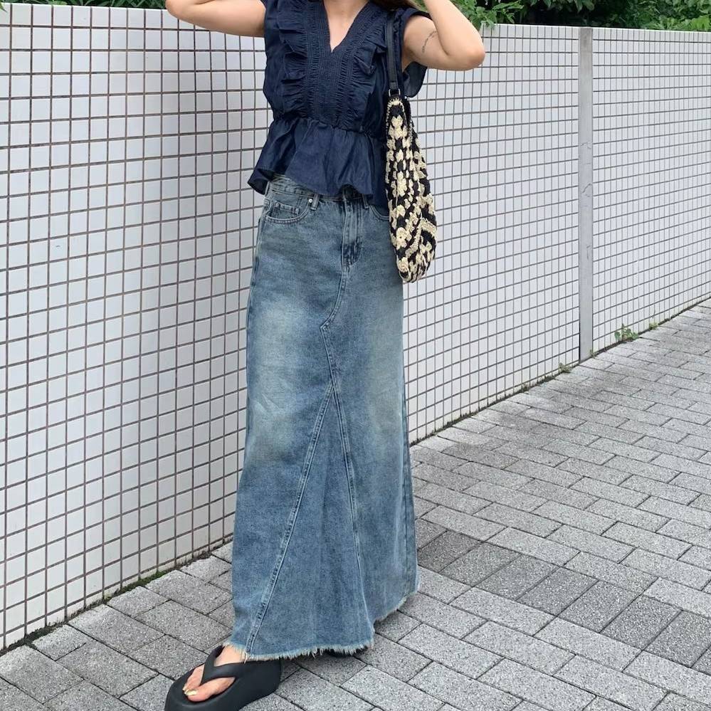 ブルーのブラウスにデニムスカートを合わせた女性