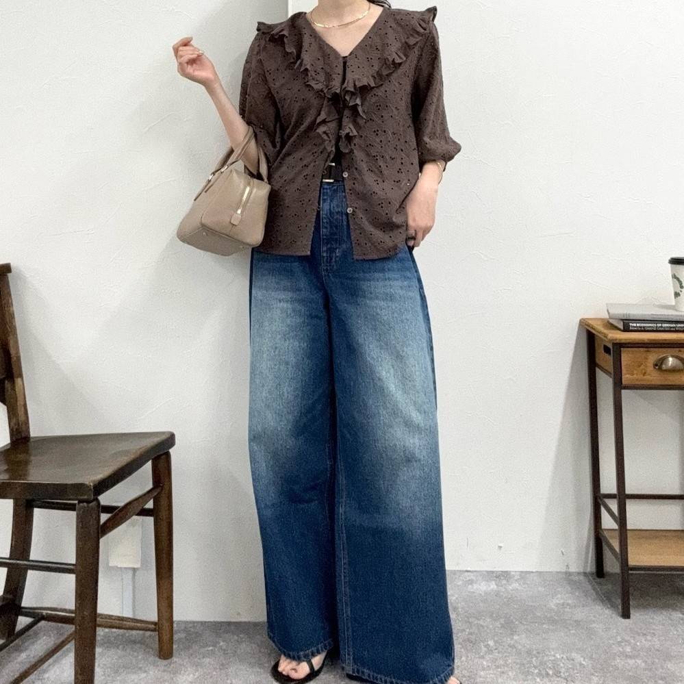 ブラウンのブラウスにデニムパンツを穿いた女性