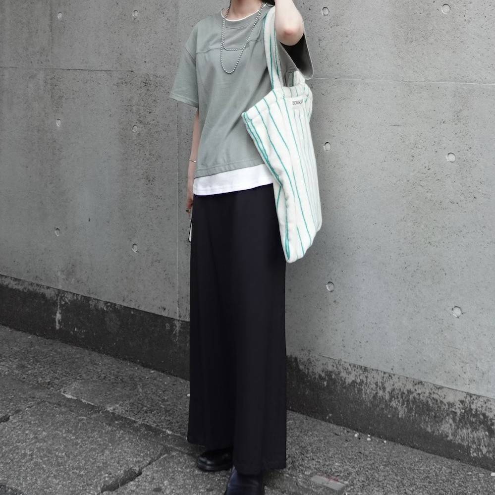 グリーンのTシャツに黒スカートを合わせた女性