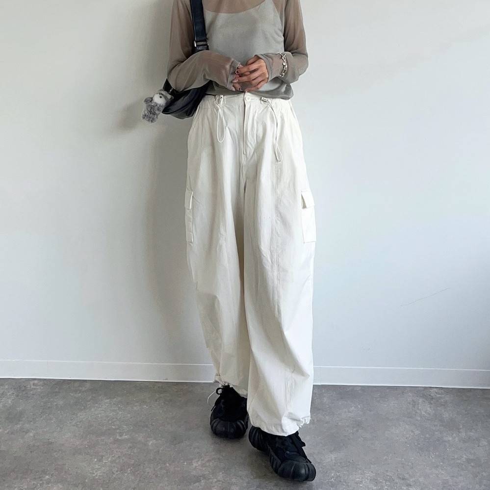 ベージュのトップスに白パンツを合わせた女性