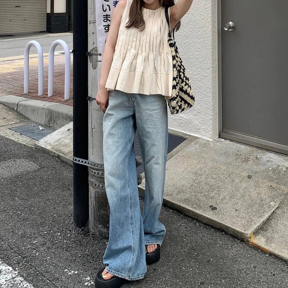 ベージュのブラウスにデニムパンツを合わせた女性