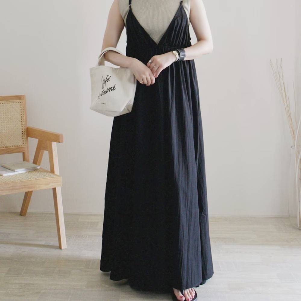 ベージュのニットに黒ワンピースを重ね着した女性