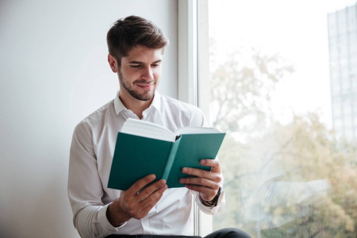 窓際で読書する男性