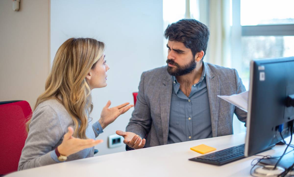 怒りながら同僚の女性と議論する男性