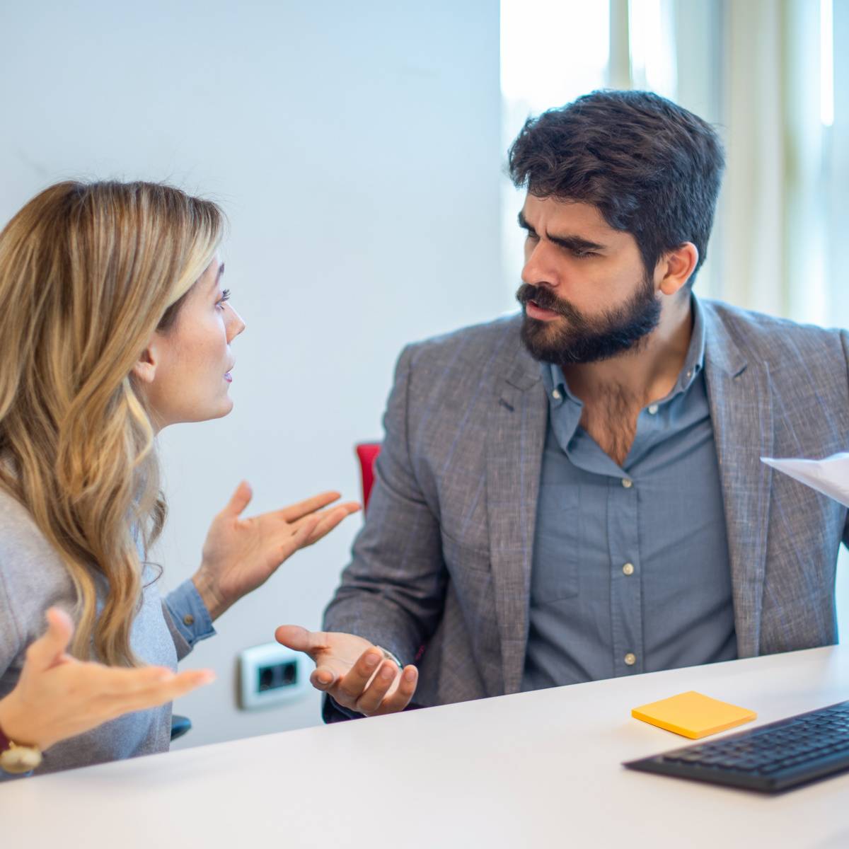 怒りながら同僚の女性と議論する男性