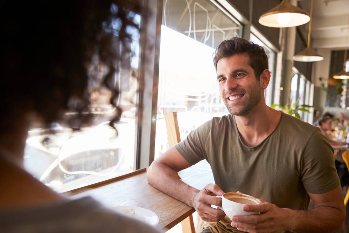 カフェの窓際の席で女性と話す男性