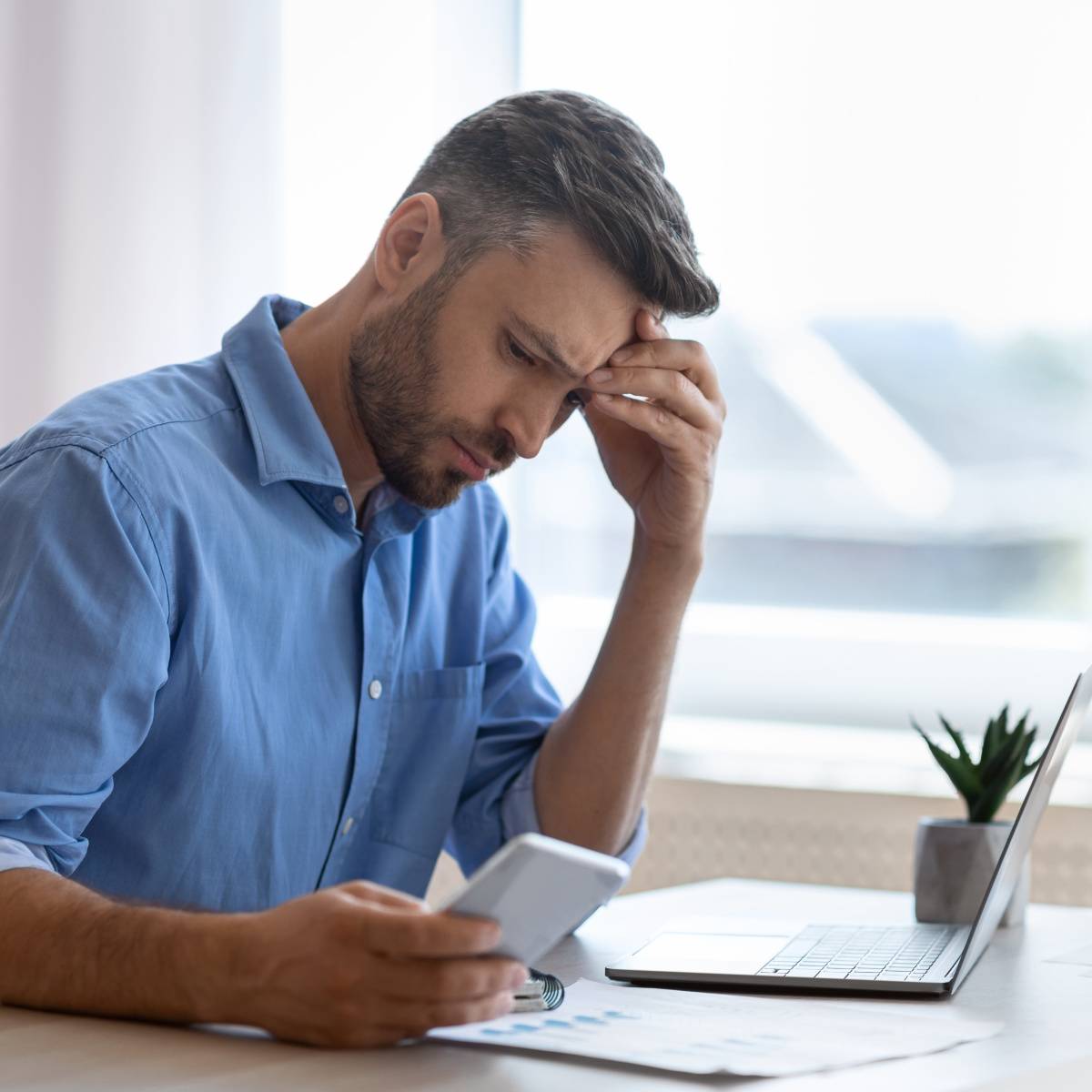 深刻な表情でスマートフォンを見る男性