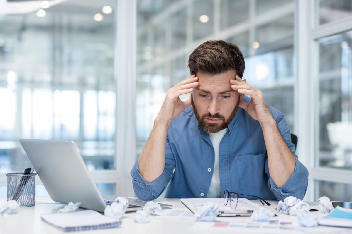 デスクに書類を広げて落ち込む男性