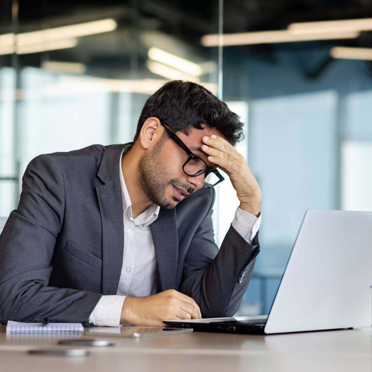 パソコンを見ながら額に手をやる男性