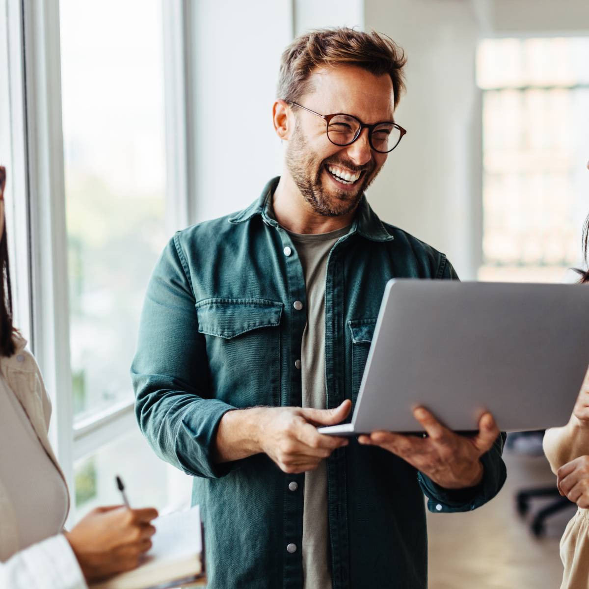 立ちながらパソコンを開いて話し合う男女