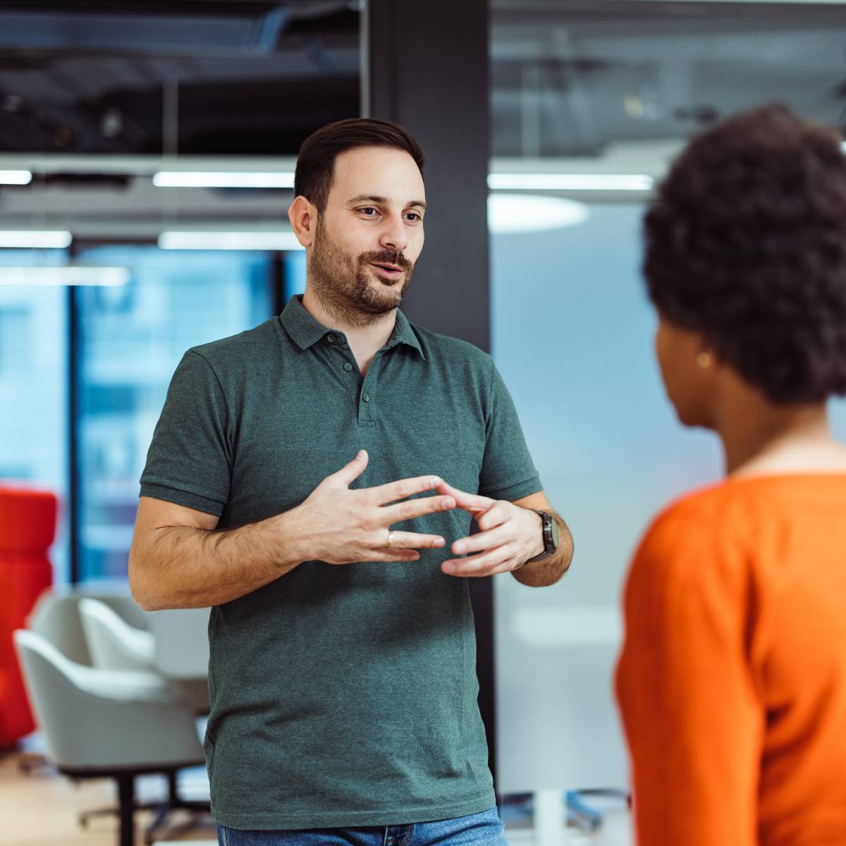 会議室で同僚と立ちながら話す男性