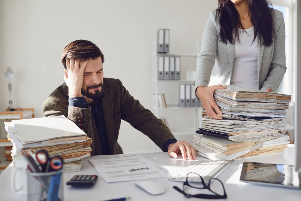 書類の山に嫌気がさす男性