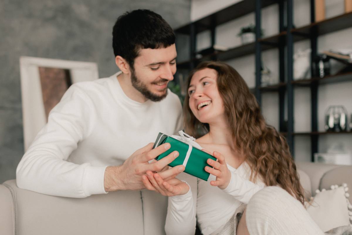 ソファに座る女性にプレゼントを渡す男性