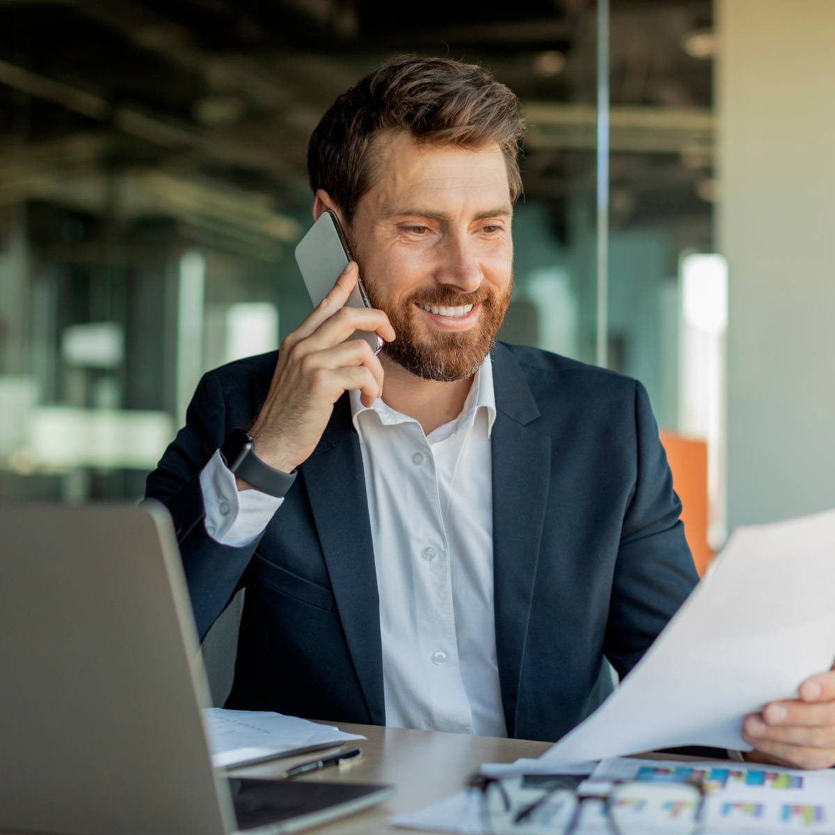 書類を手に持ちながら電話する男性