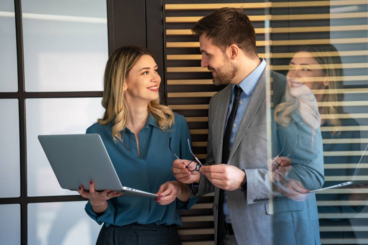 パソコンを持つ女性に話しかける男性