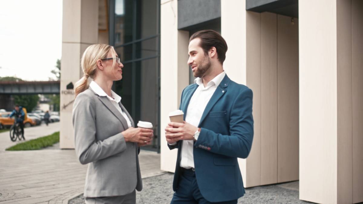 コーヒーを持ちながら立ち話する男女