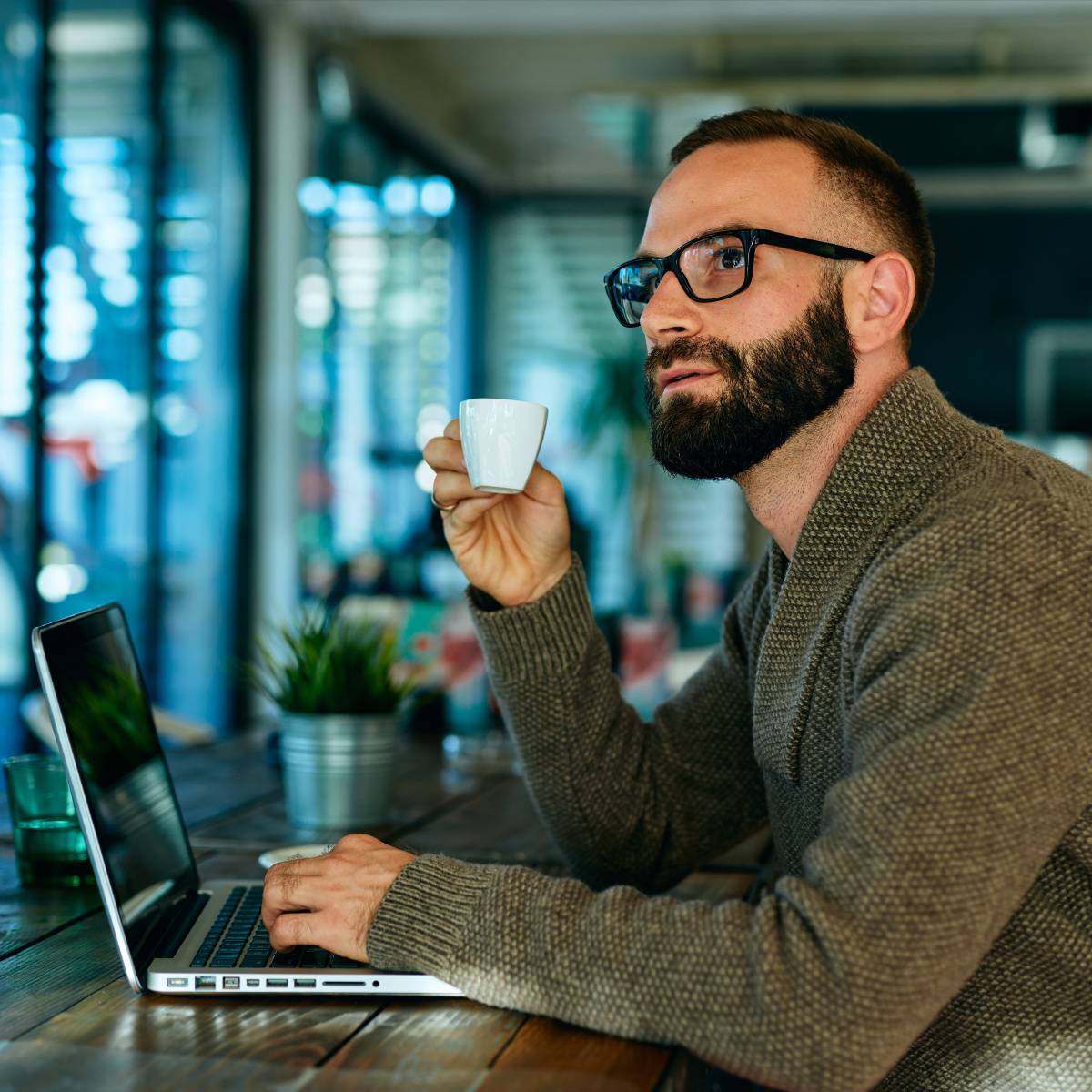カフェでコーヒーを飲みながら仕事する男性
