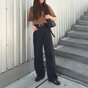  ブラウンのTシャツにデニムパンツを合わせた女性 