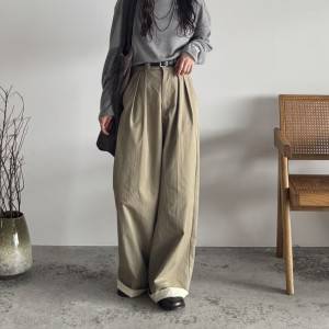  グレーのトップスにベージュのパンツを合わせた女性 