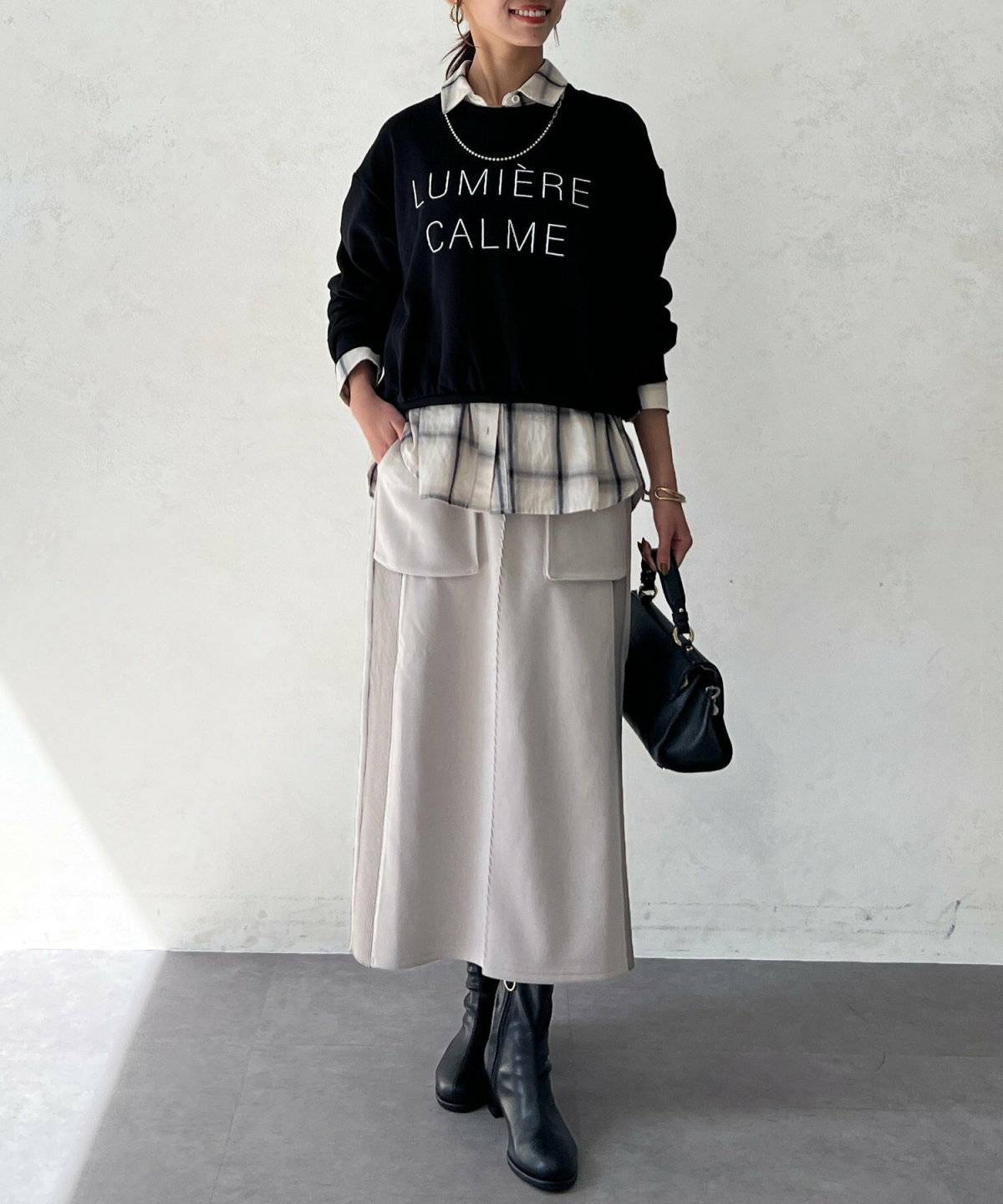 黒スウェットにベージュのスカートを合わせた女性