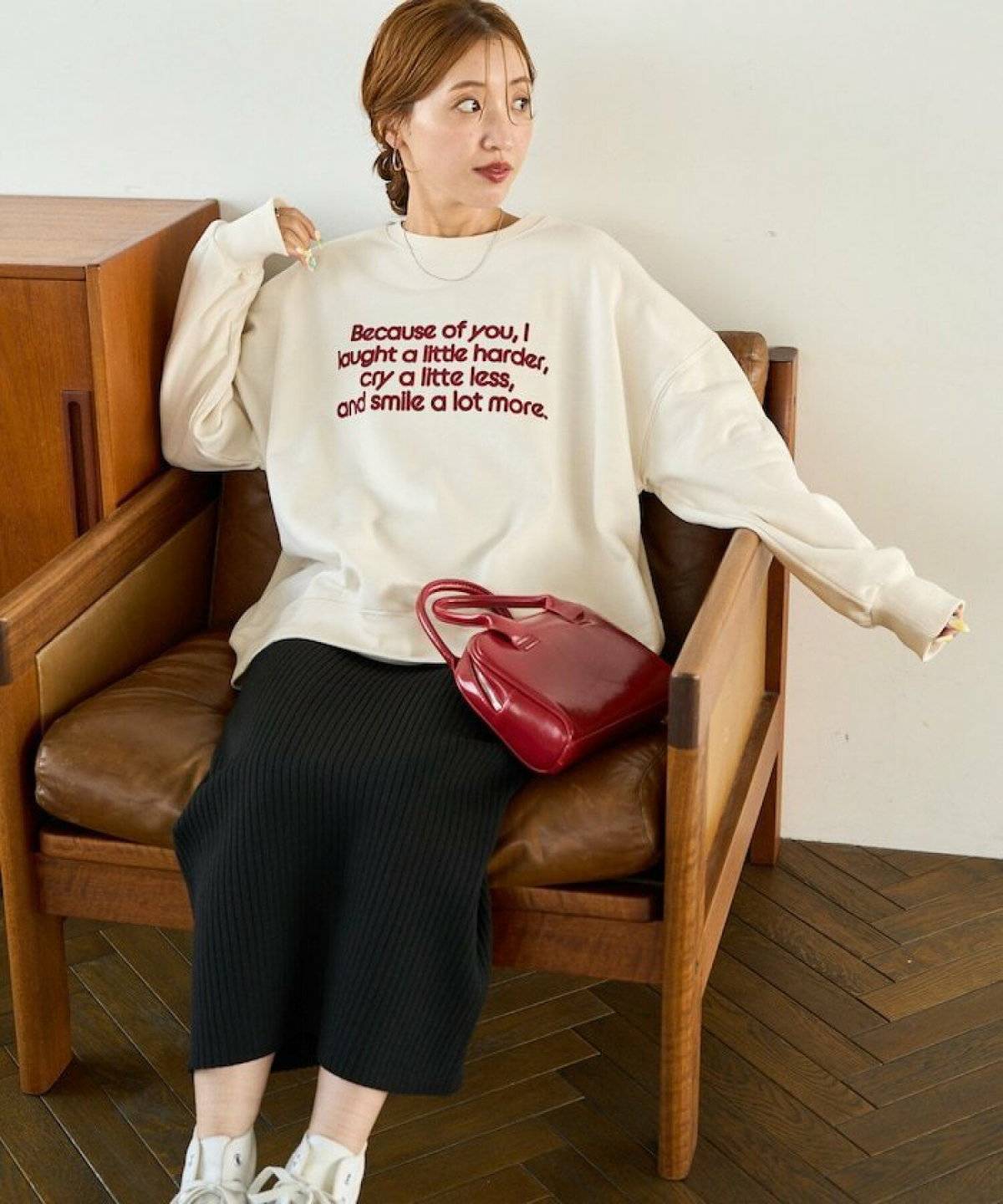 ベージュのスウェットに黒スカートを合わせた女性