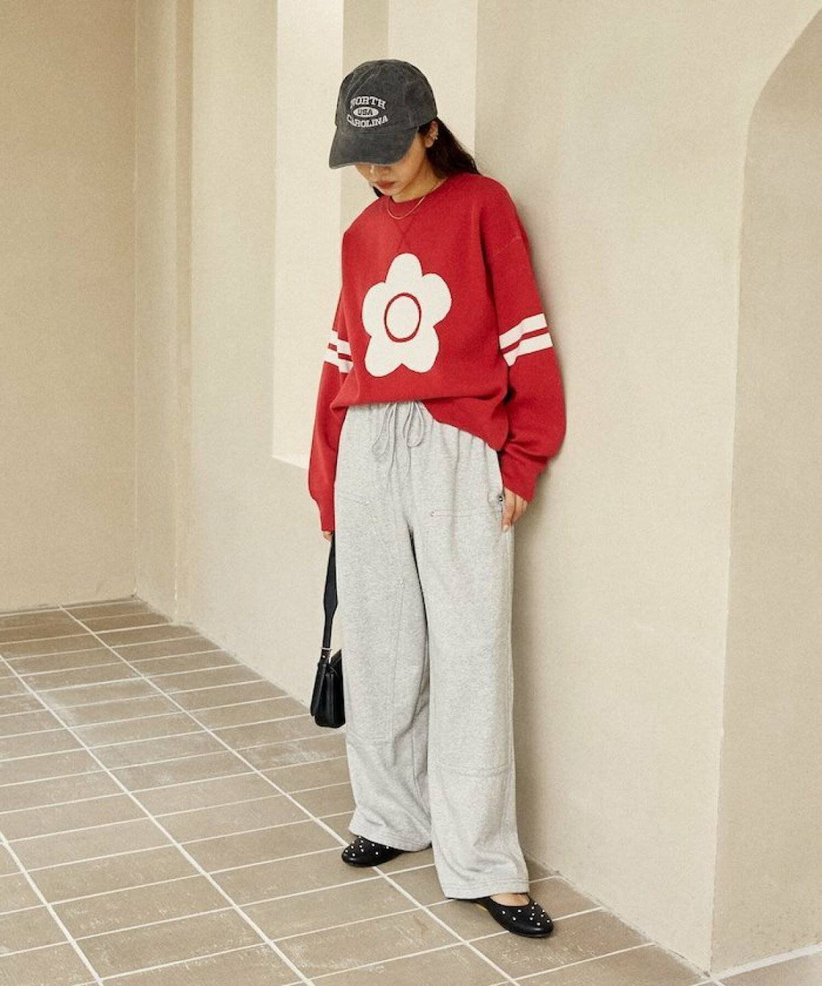 赤ニットにベージュのスウェットパンツを合わせた女性