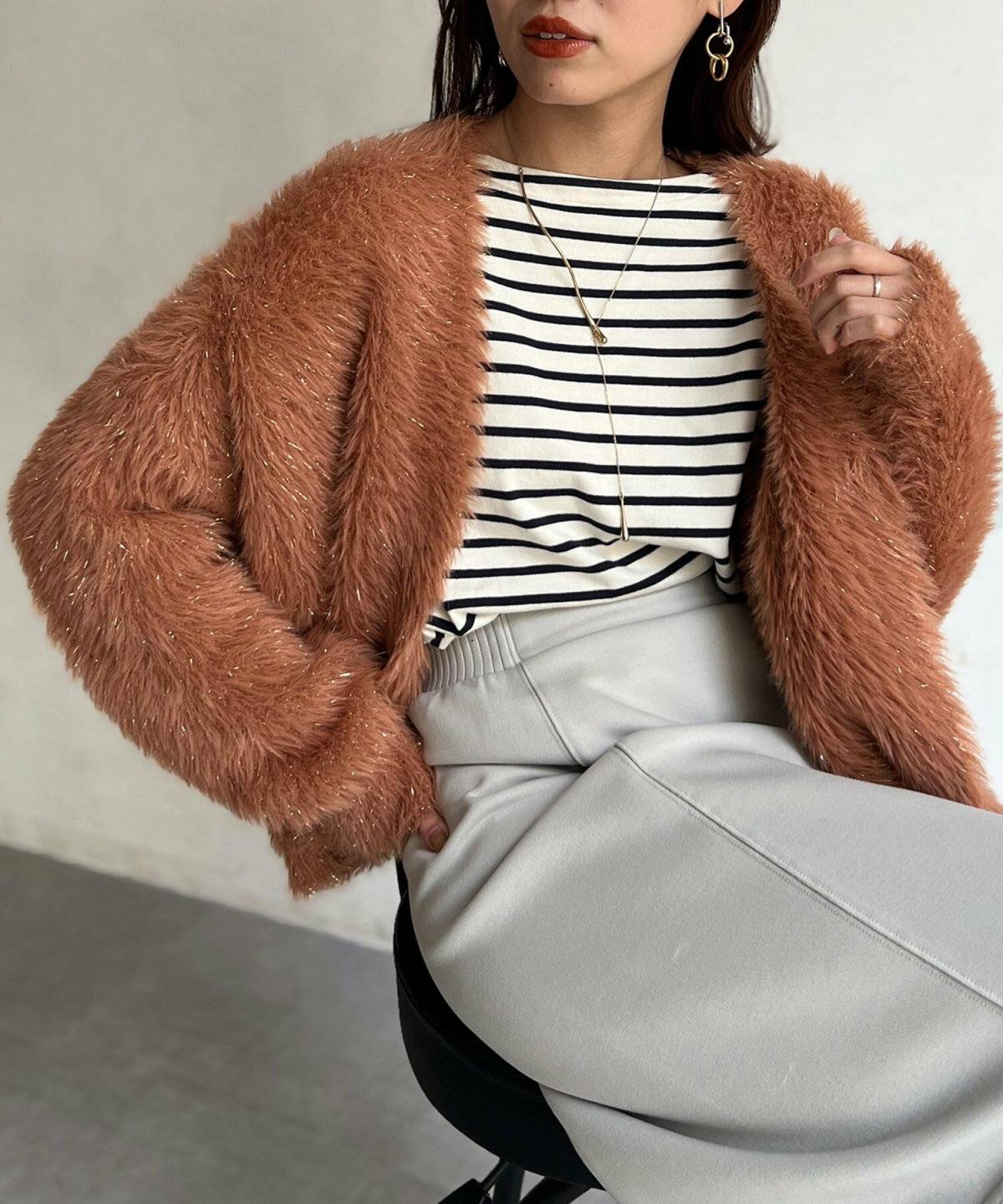 黒トップスにオレンジのカーディガンを羽織ってスカートを合わせた女性