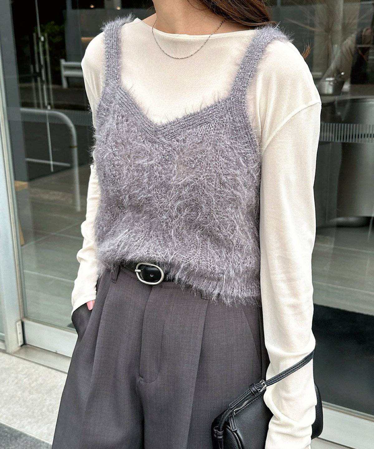 モノトーンコーデにグレーのニットキャミソールを重ねた女性