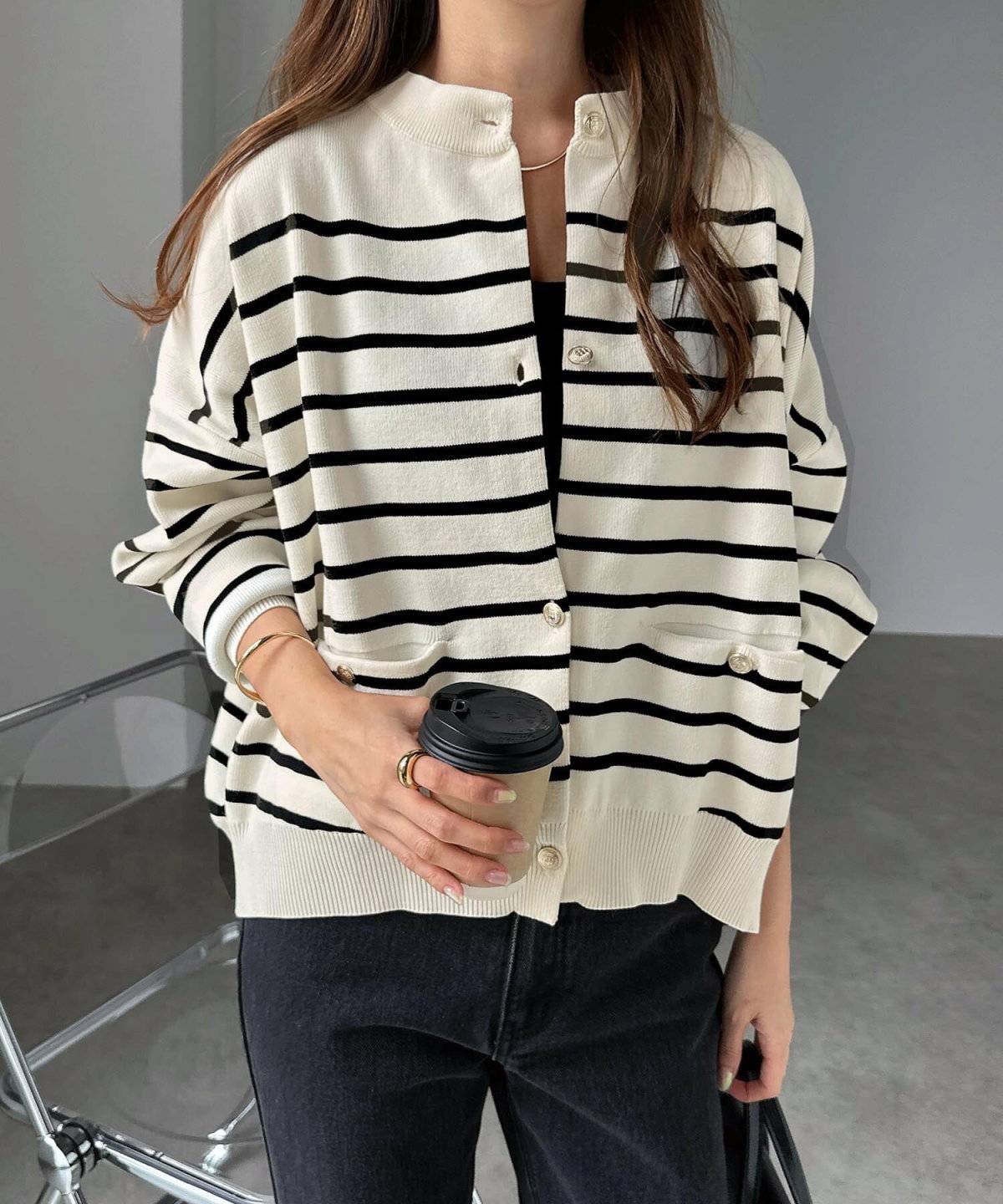 ブラックコーデにボーダー柄カーディガンを羽織った女性