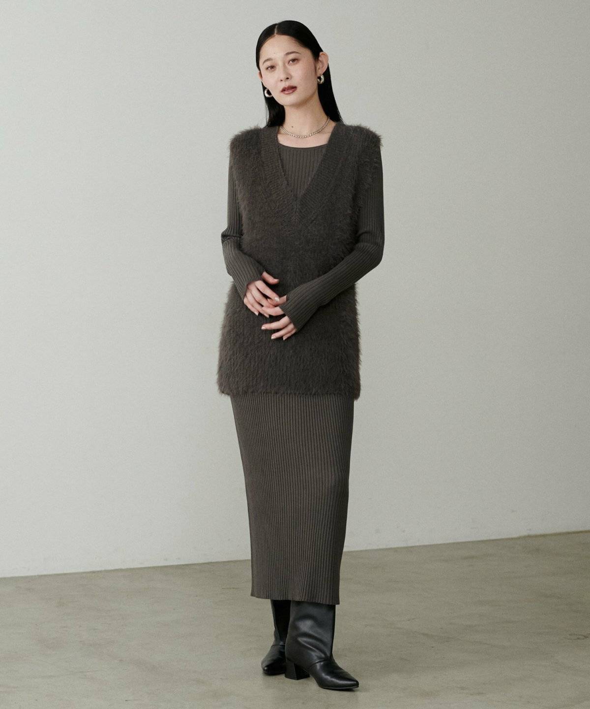 ニットワンピースにフェザーベストを重ねた女性