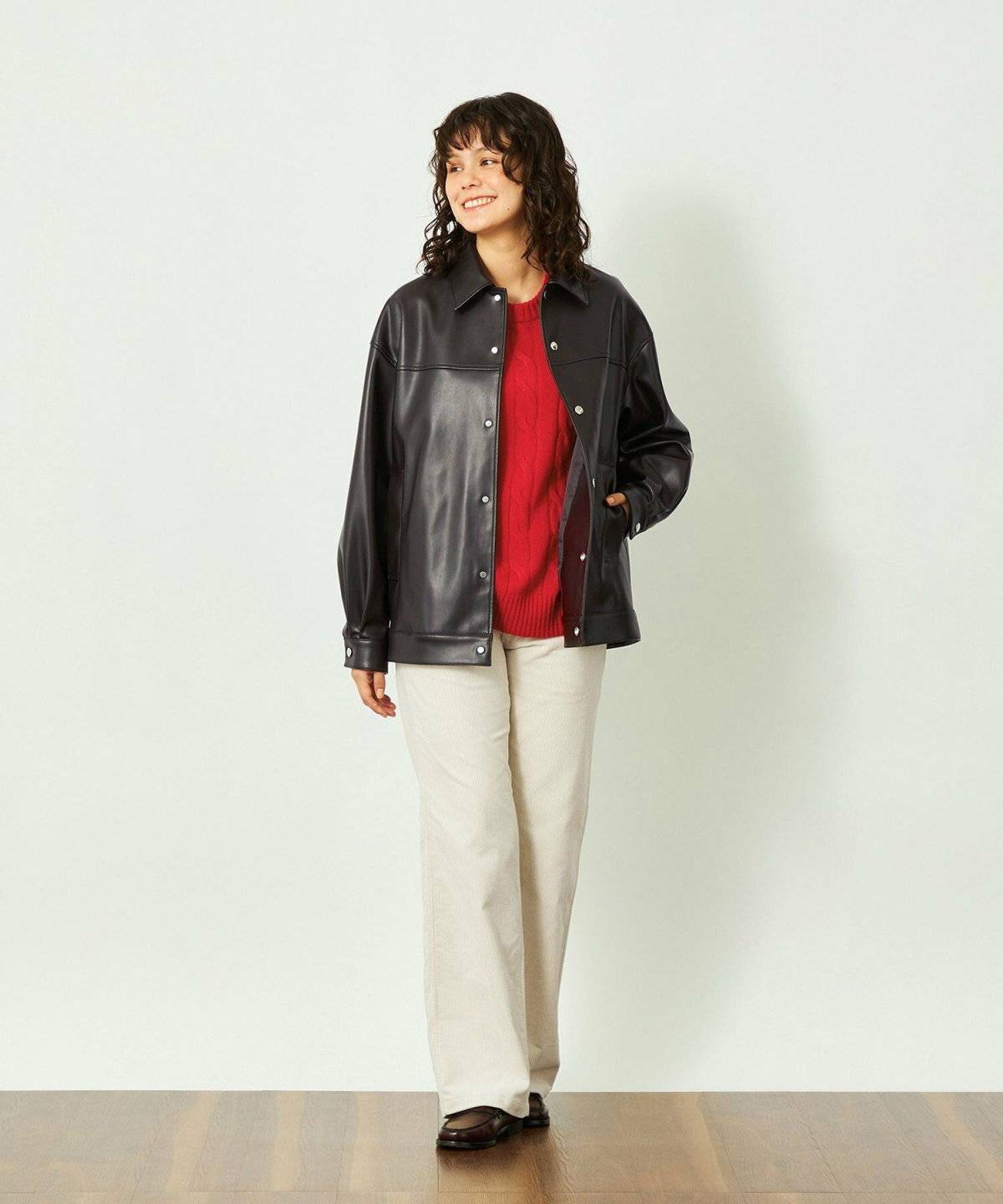 赤ニットに白パンツを合わせてブラウンのブルゾンを羽織った女性