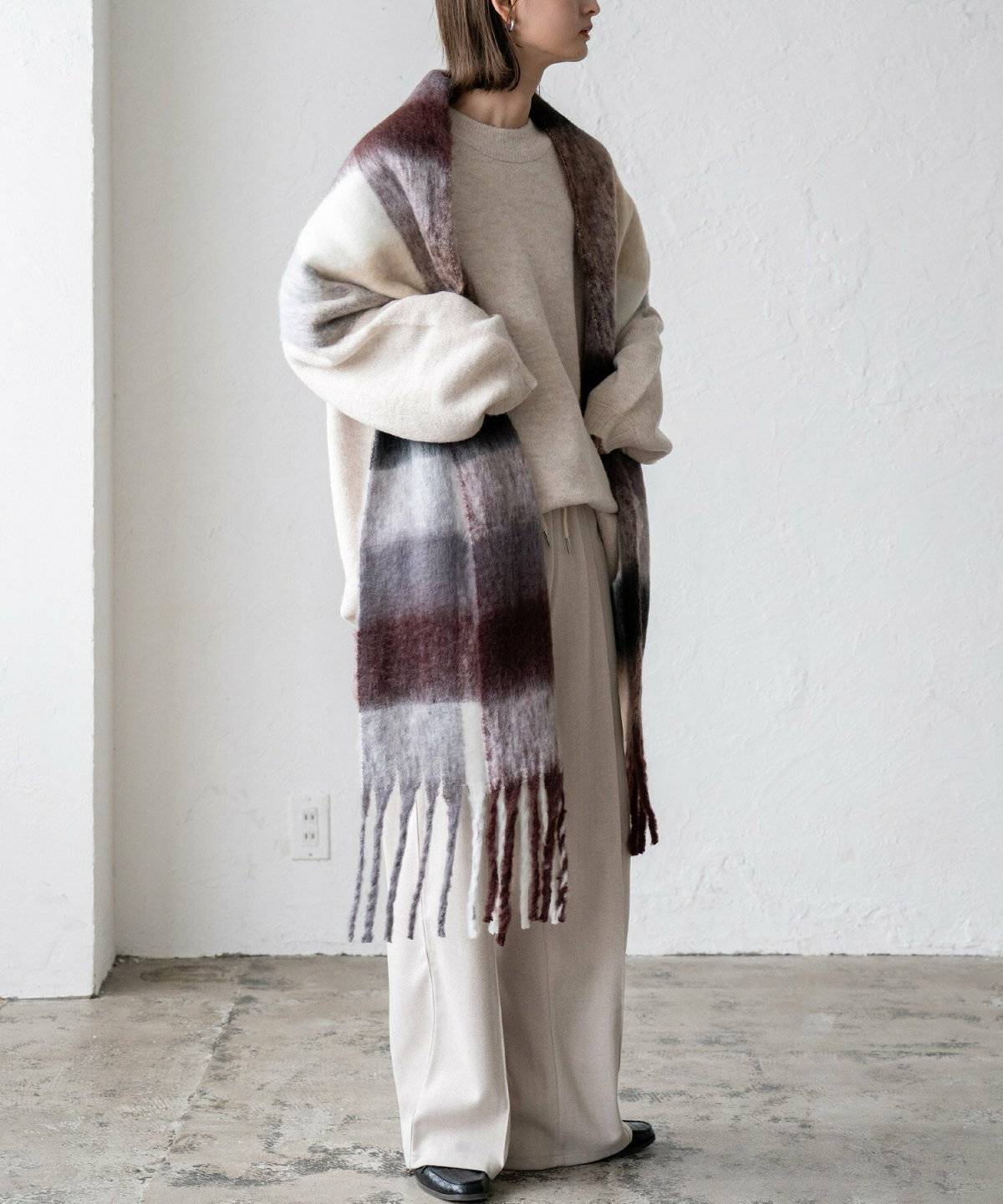 淡色コーデにチェック柄マフラーを巻いた女性