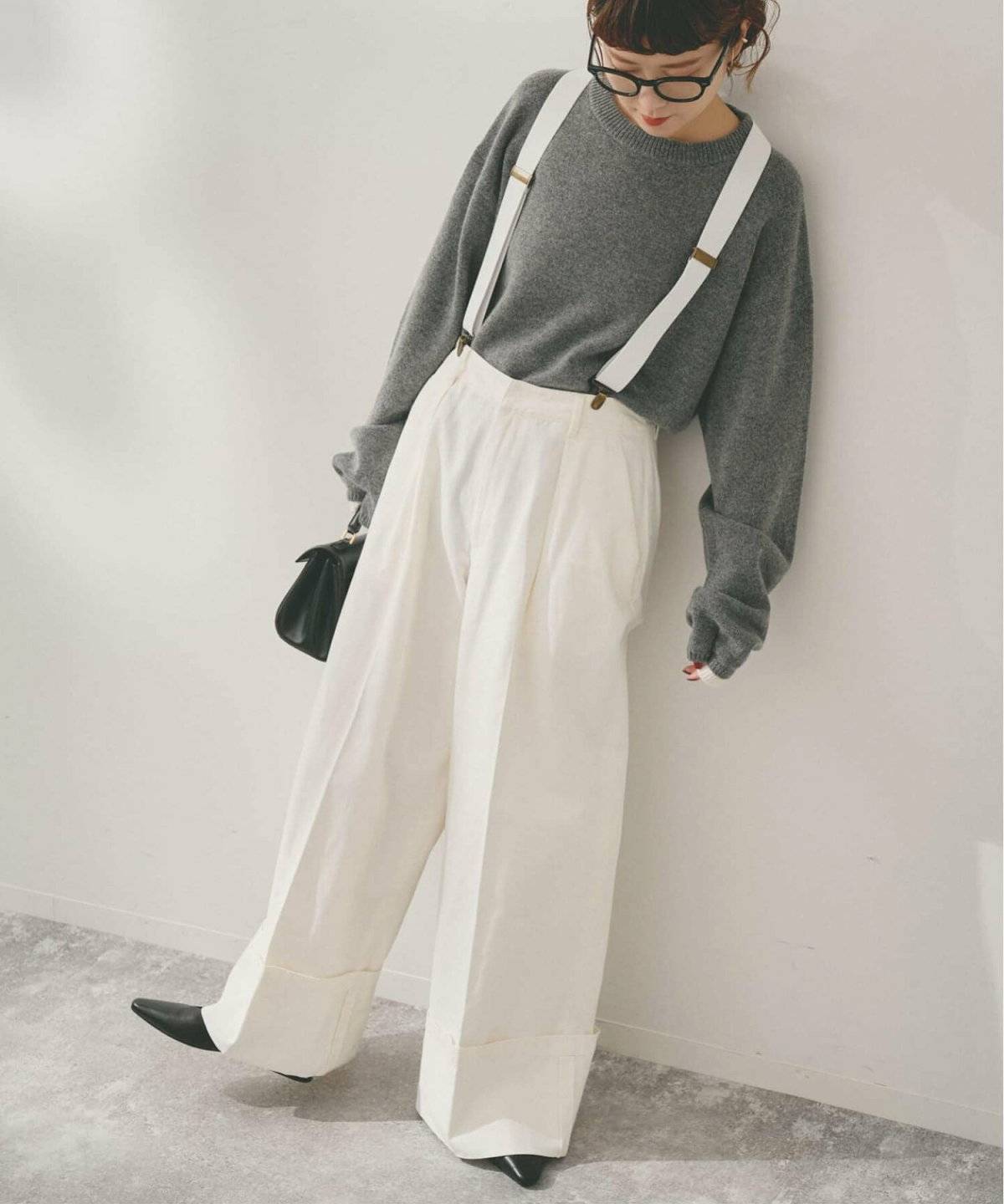 グレーニットにサスペンダー付きチノパンを合わせた女性