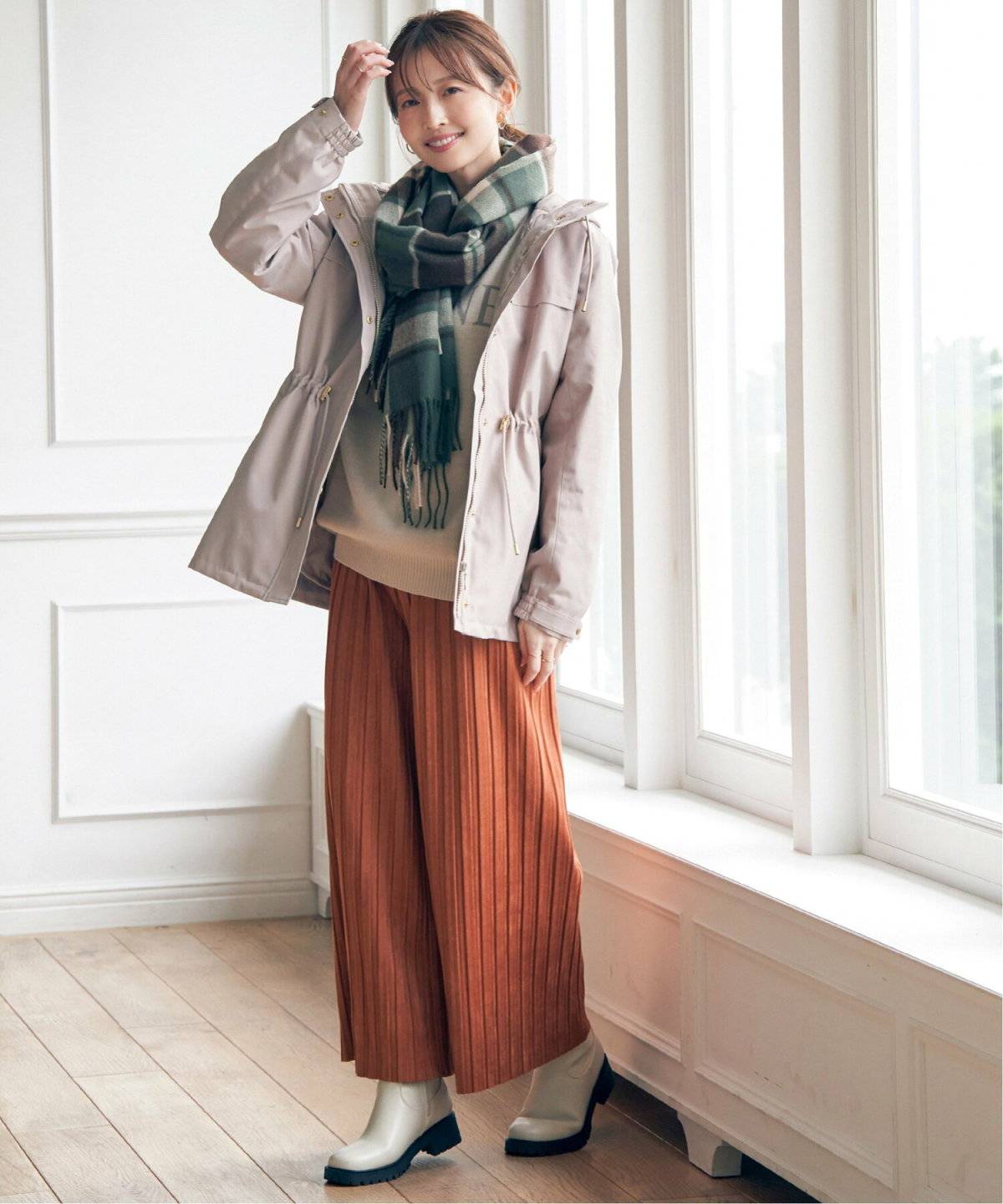 プリーツパンツにチェック柄ストールを巻いた女性