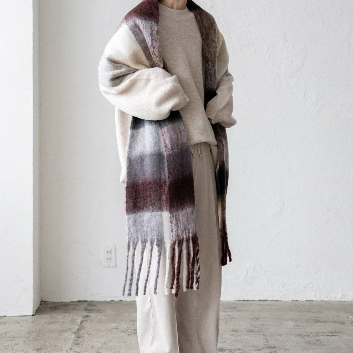 淡色コーデにチェック柄ストールを巻いた女性