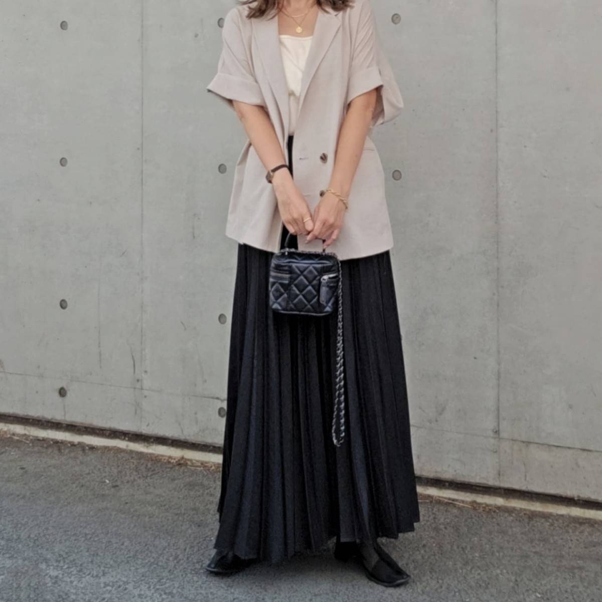 ベージュのトップスに黒スカートを合わせた女性
