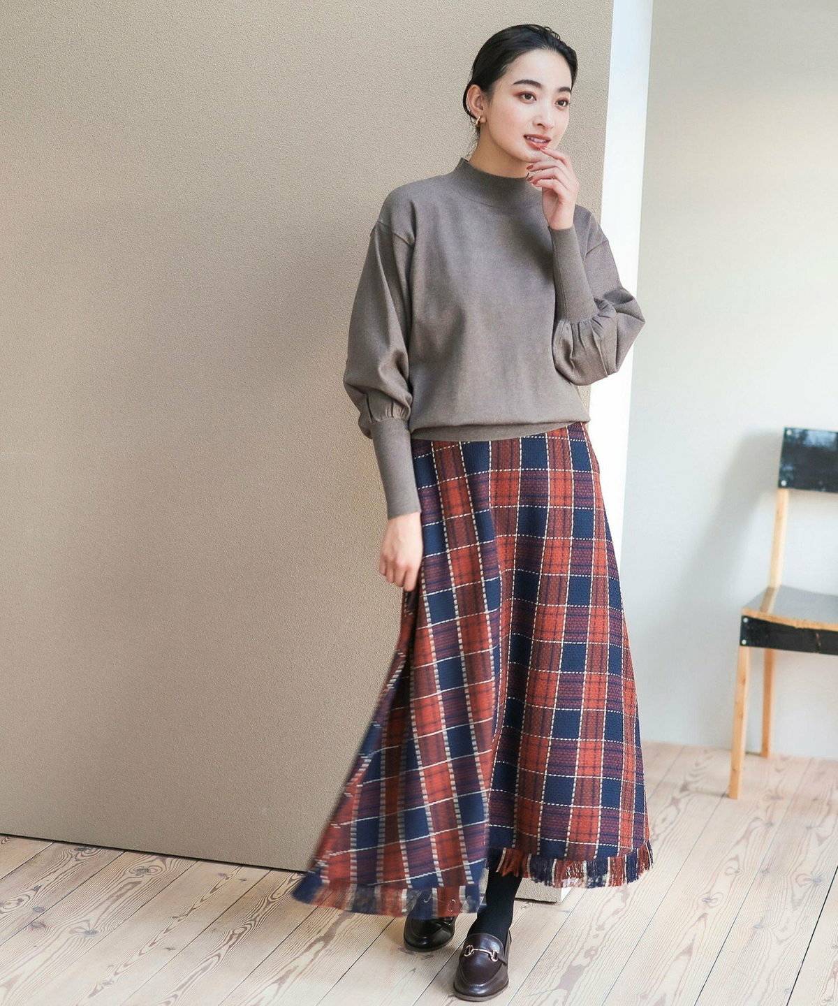 ニットにチェック柄スカートを合わせた女性