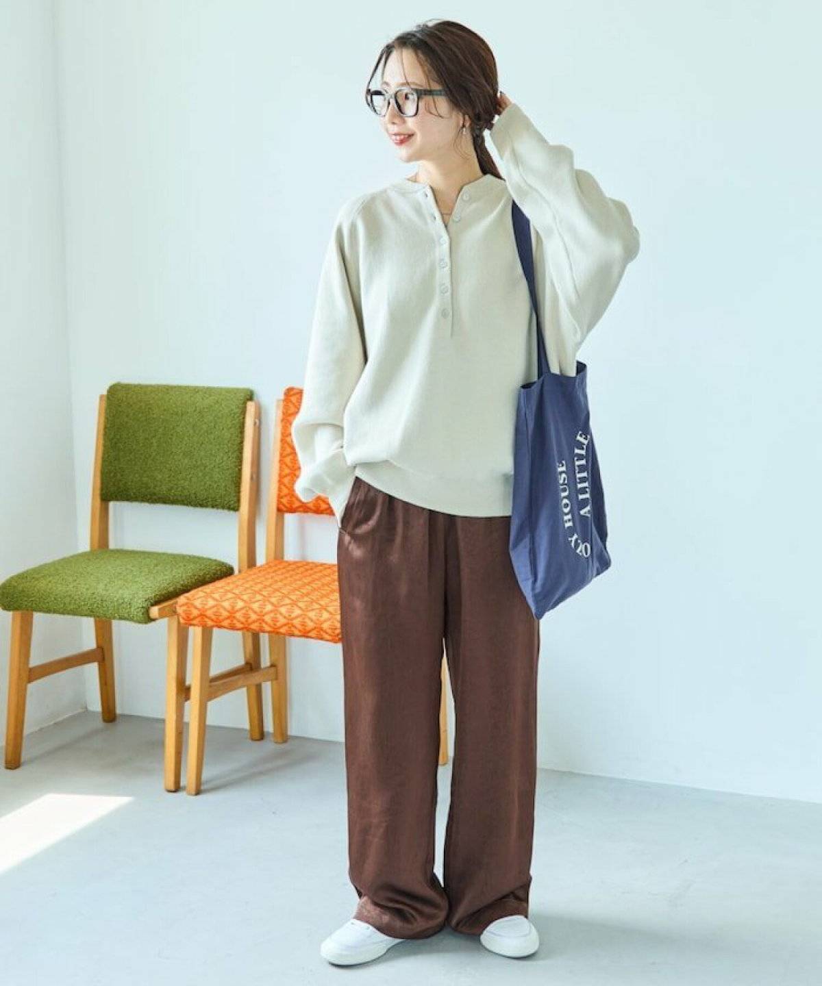 ベージュニットにブラウンのパンツを合わせた女性