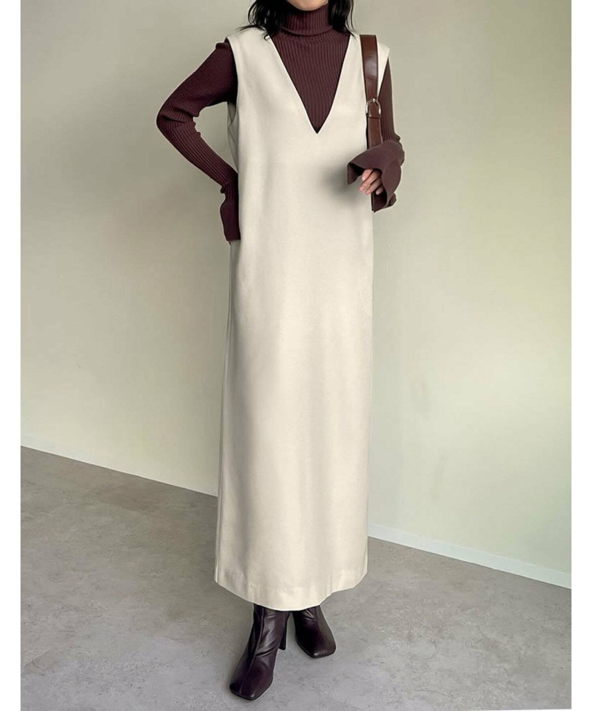 ボルドーニットにジャンパースカートを合わせた女性