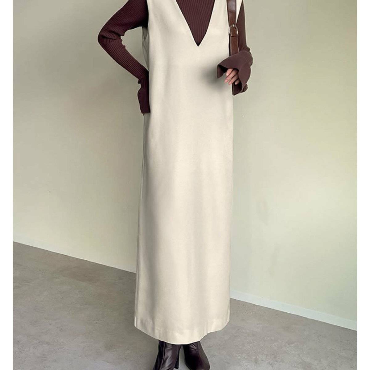 ボルドーニットにジャンパースカートを合わせた女性